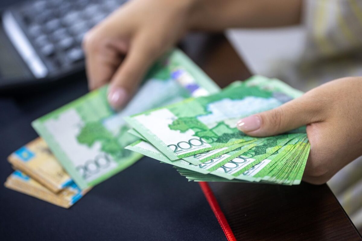 about-img Person counting stacks of Uzbekistani som banknotes, showcasing financial transactions.