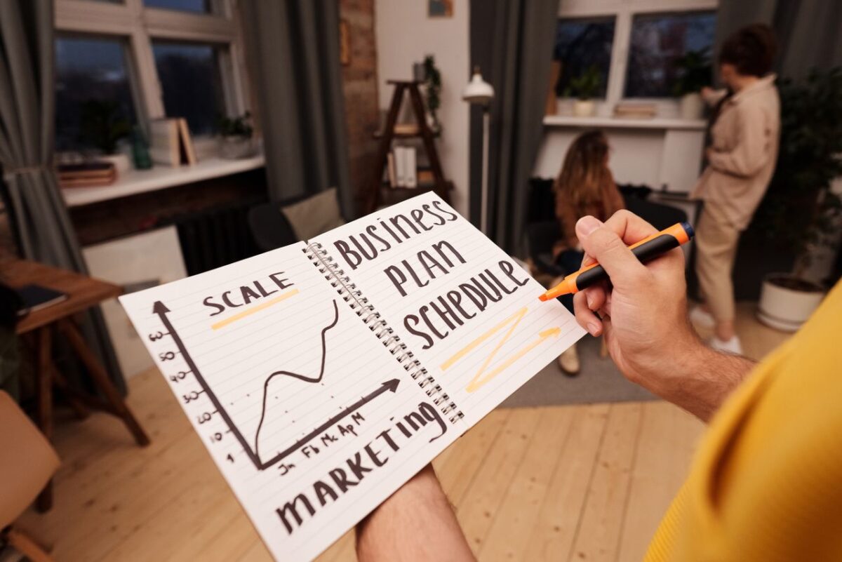 about-02 Person holding a notebook with planning details and graph for business strategy indoors.