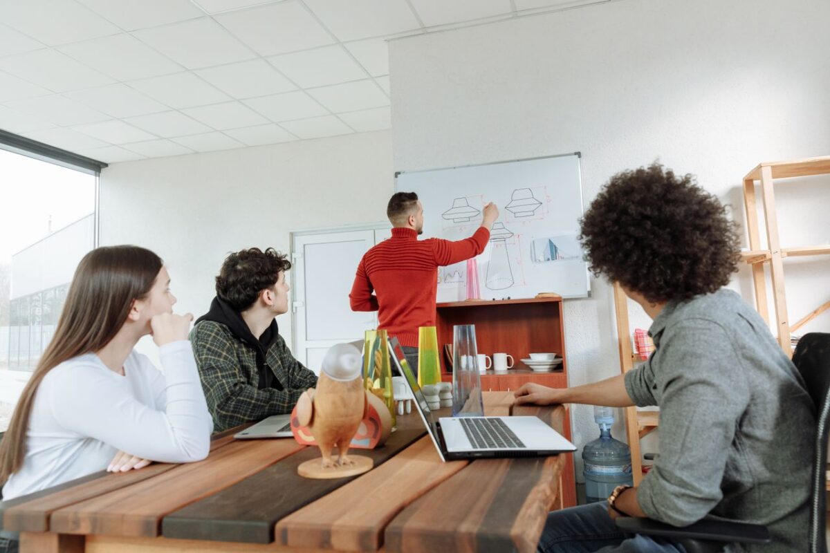 ours-journey Group of young adults collaborating on design ideas in a modern office setting.